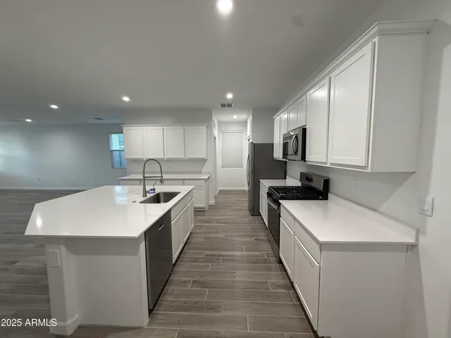 a large white kitchen with a white stove top oven and sink