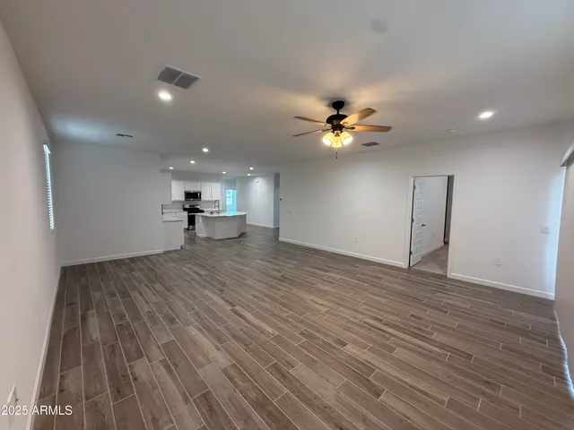 a view of an empty room and chandelier fan
