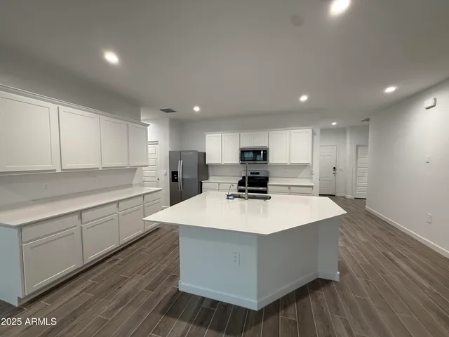 a large white kitchen with wooden floor cabinetry and a refrigerator
