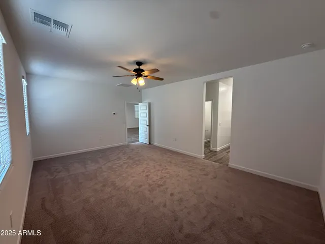 a view of an empty room with a chandelier fan