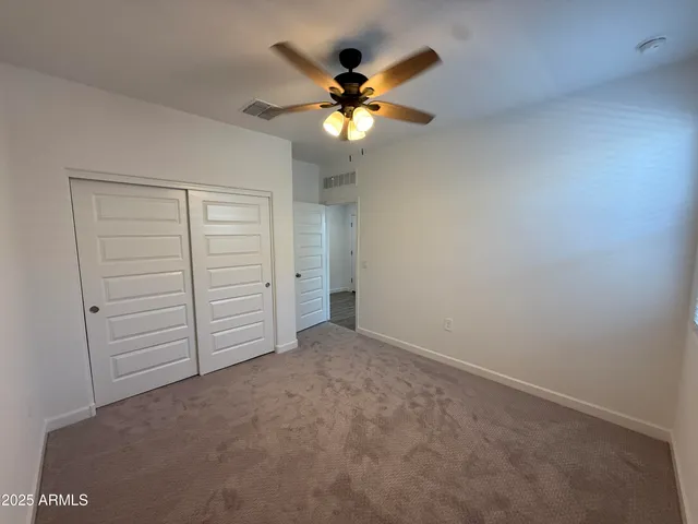 an empty room with closet and a ceiling fan