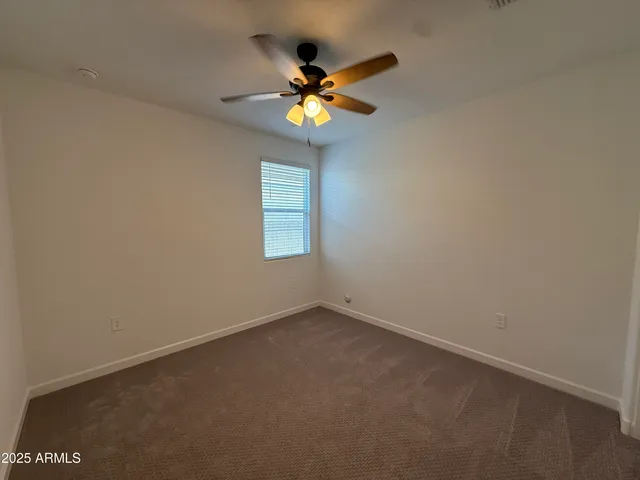 an empty room with a window and a ceiling fan