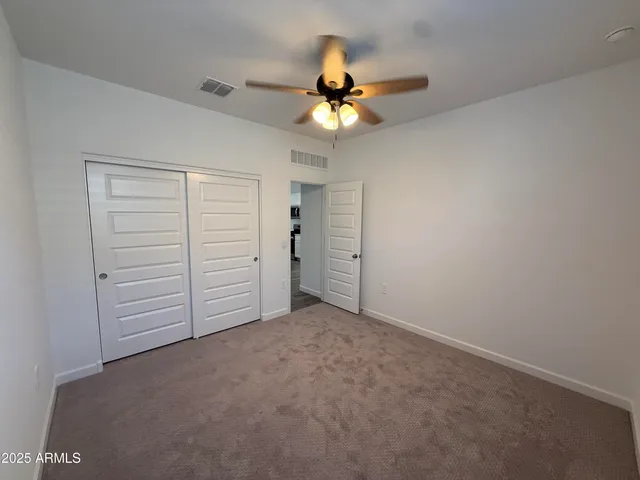 an empty room with closet and a ceiling fan