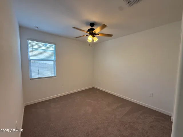 an empty room with a window and a ceiling fan
