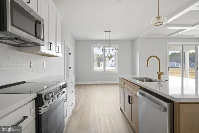 a view of a kitchen with wooden floor and white cabinets