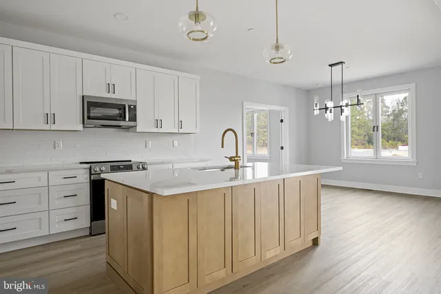a view of an empty room with wooden floor and a ceiling fan