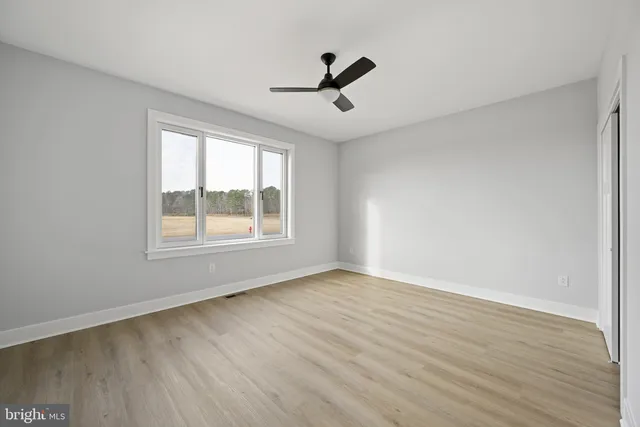 an empty room with wooden floor and a ceiling fan