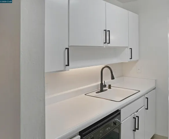 a close view of a sink a stove and cabinets
