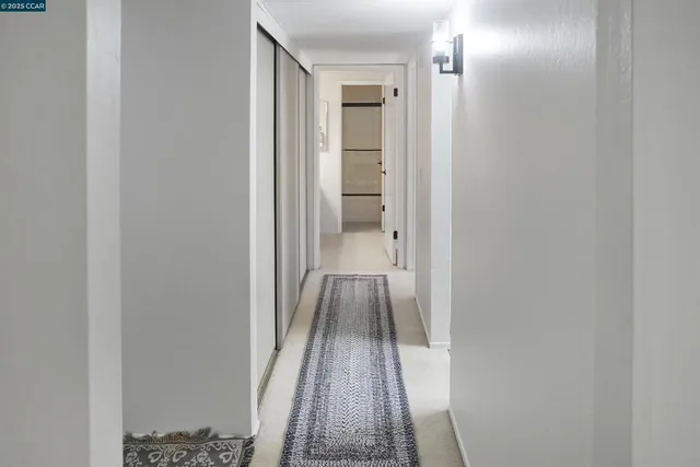 a view of a hallway with wooden floor and a bathroom
