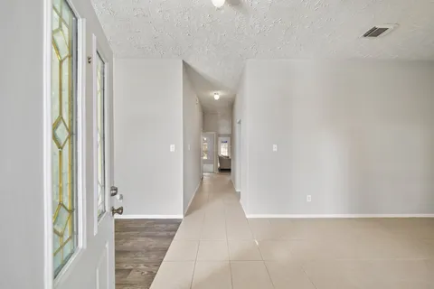 a view of a hallway with wooden floor and a bathroom