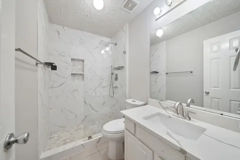 a bathroom with a sink a toilet and shower