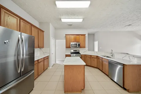 a large kitchen with granite countertop a sink refrigerator and cabinets