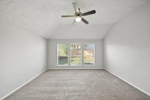 an empty room with ceiling fan and windows