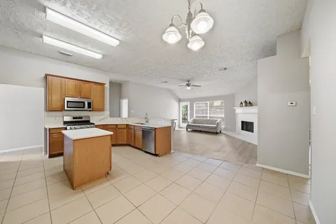 a kitchen with stainless steel appliances granite countertop a stove top oven a sink dishwasher and a refrigerator with wooden floor