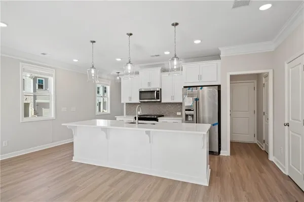 a large kitchen with stainless steel appliances kitchen island a large counter top and a wooden floors