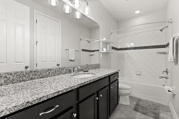 a bathroom with a granite countertop sink a toilet and shower