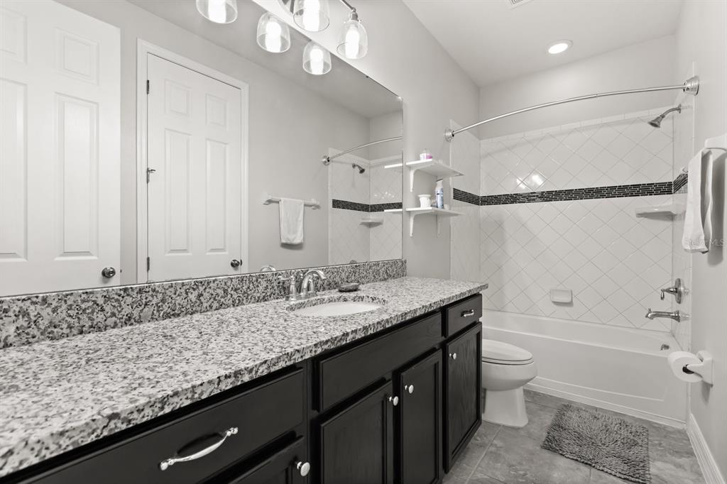 2417 Chateau Loop Kissimmee, FL 34741 - Photo 13 of 16 a bathroom with a granite countertop sink a toilet and shower