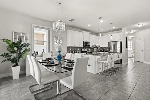 a kitchen with stainless steel appliances kitchen island granite countertop a refrigerator a stove a sink a dining table and chairs