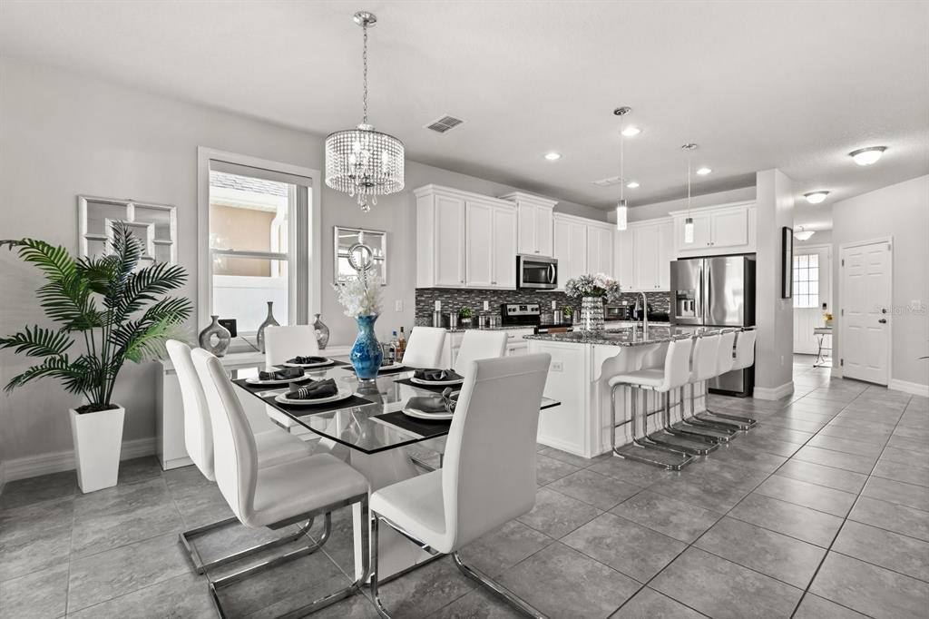 2417 Chateau Loop Kissimmee, FL 34741 - Photo 3 of 16 a kitchen with stainless steel appliances kitchen island granite countertop a refrigerator a stove a sink a dining table and chairs