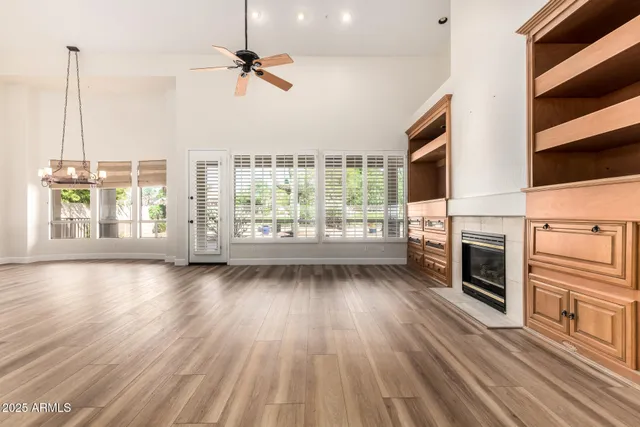 an empty room with wooden floor fan and windows