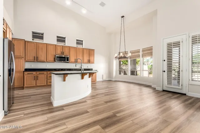 a kitchen with stainless steel appliances granite countertop a refrigerator a stove and a wooden floors