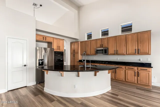 a kitchen with stainless steel appliances granite countertop a sink a stove and a wooden floors