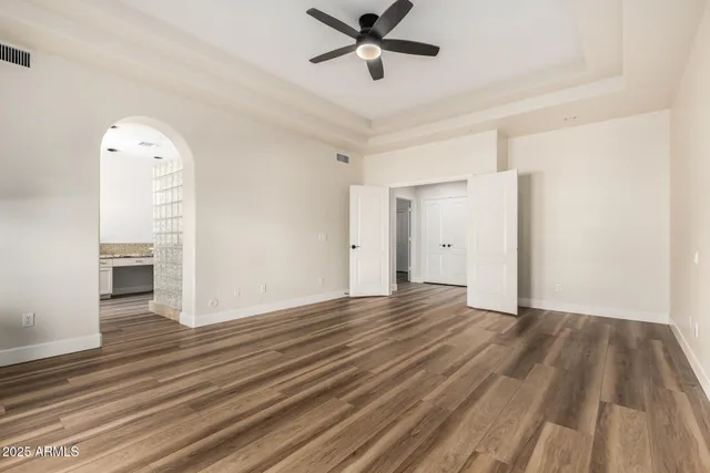 a view of empty room with wooden floor and ceiling fan