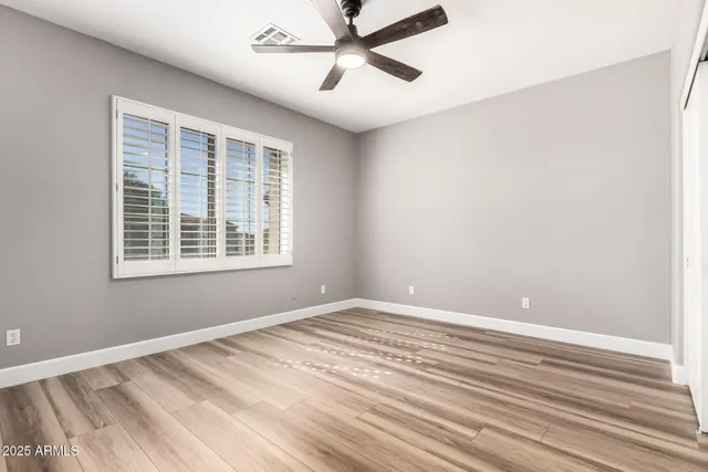 a view of empty room with wooden floor and fan