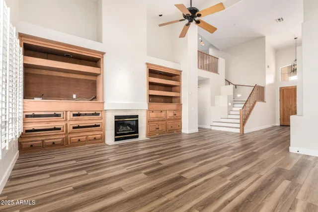 a view of a livingroom with wooden floor a ceiling fan a fireplace and entryway