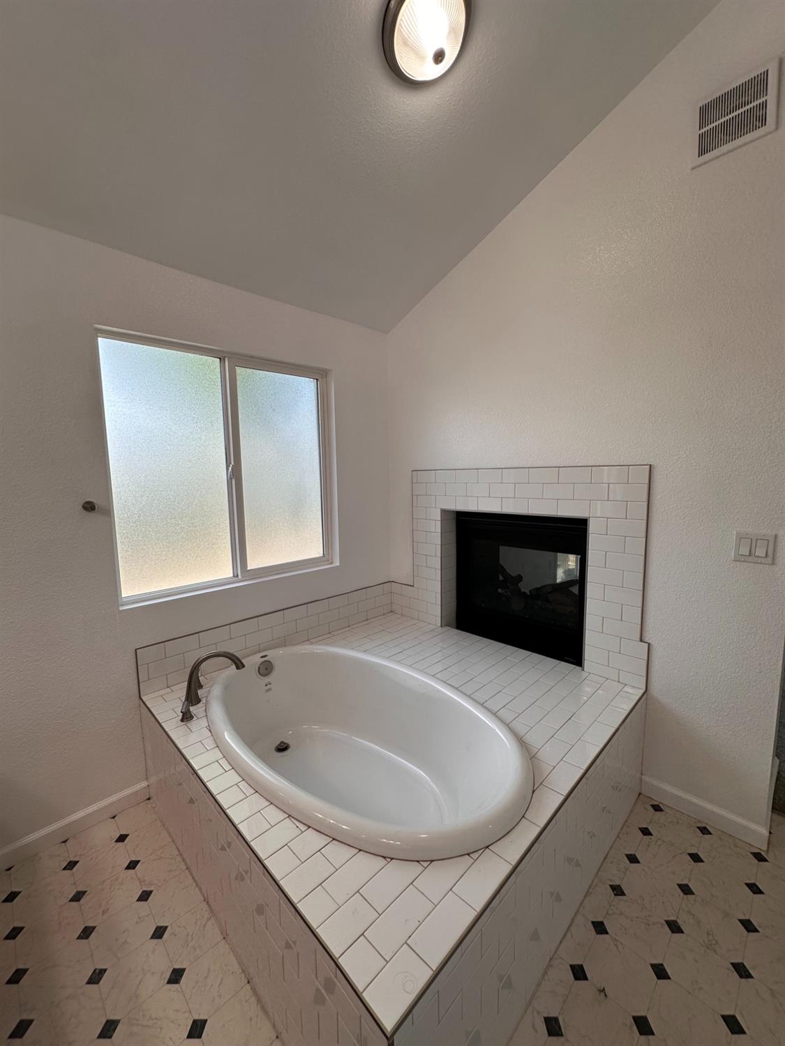 911 Toro Lane Lathrop, CA 95330 - Photo 11 of 36 Soaking tub in Primary Bedroom, double sided, see thru fireplace, frosted privacy window, and patterned floor tiles