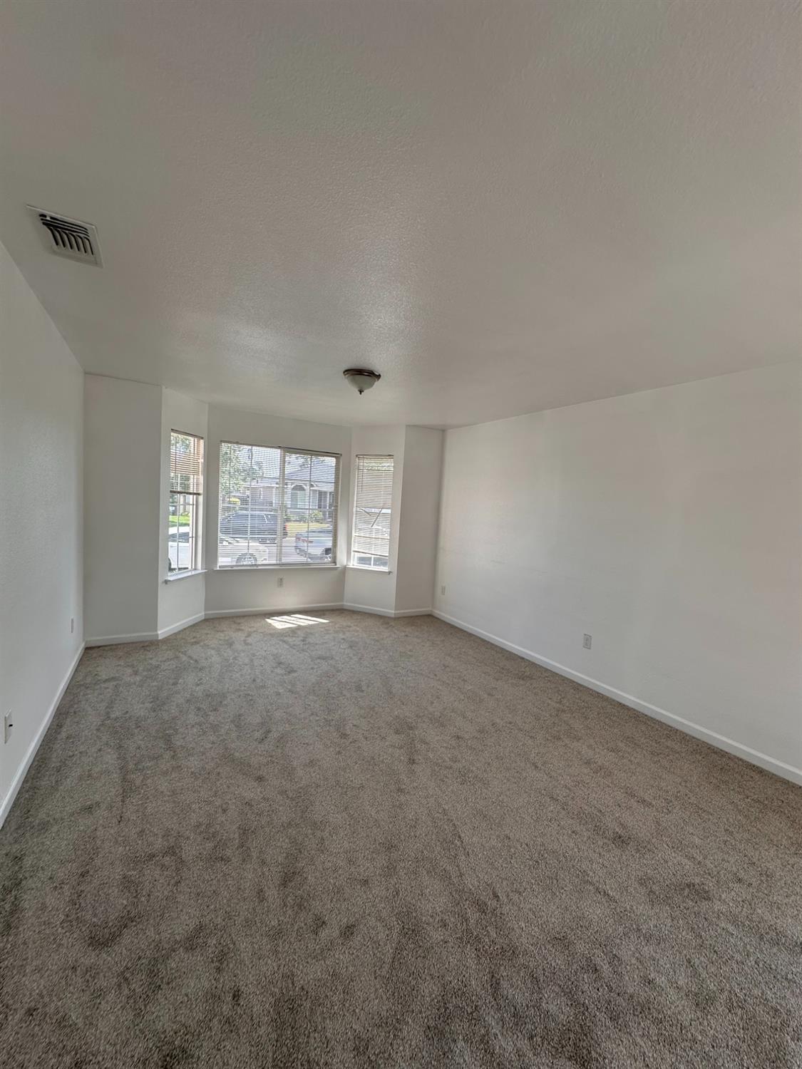 911 Toro Lane Lathrop, CA 95330 - Photo 14 of 36 Spacious living room featuring neutral carpeting, white walls, a bay window with blinds, and a semi-flush mount ceiling light