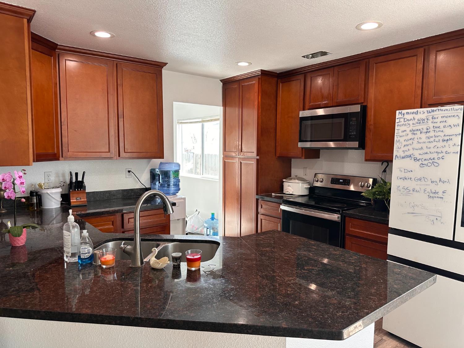 911 Toro Lane Lathrop, CA 95330 - Photo 2 of 36 Kitchen featuring rich wood cabinetry, Granite countertops, stainless steel appliances including a microwave and range, and double-sink with a high-arc faucet