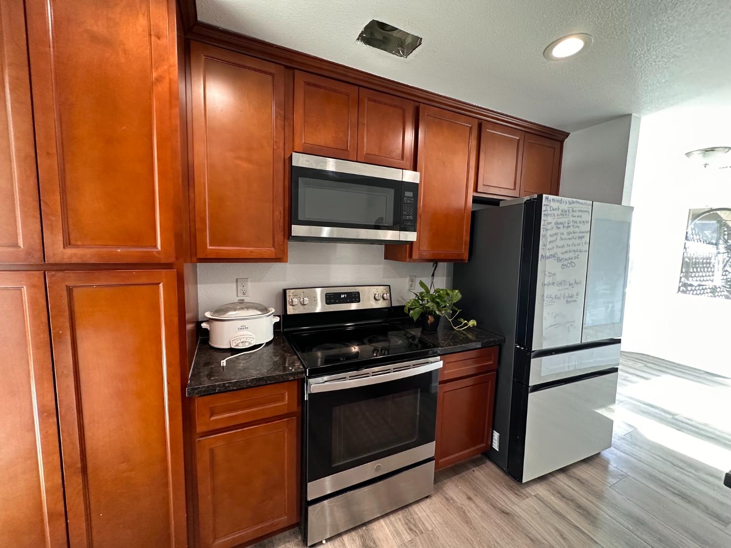 911 Toro Lane Lathrop, CA 95330 - Photo 6 of 36 Kitchen featuring rich wood cabinetry, stainless steel appliances, Granite countertops, and wood-finish flooring