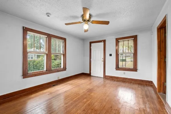a view of an empty room with wooden floor and a window