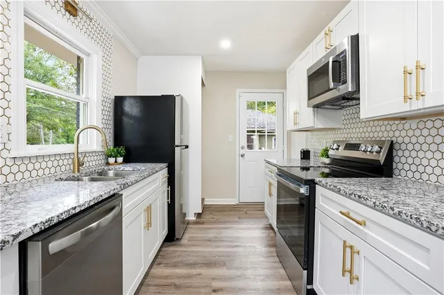 a kitchen with stainless steel appliances granite countertop a sink stove microwave and refrigerator