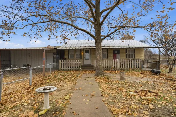 a view of a house with a large tree and wooden fence