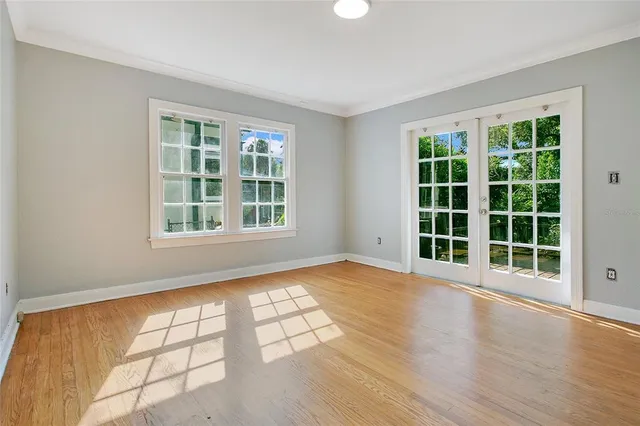 a view of an empty room with a window and wooden floor