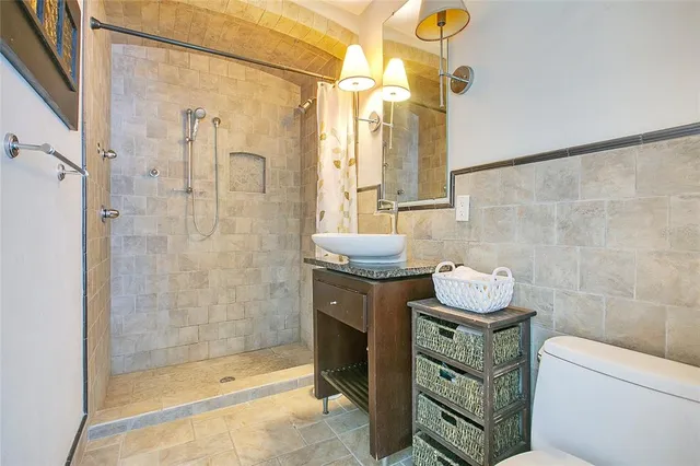 a bathroom with a granite countertop sink a toilet and shower