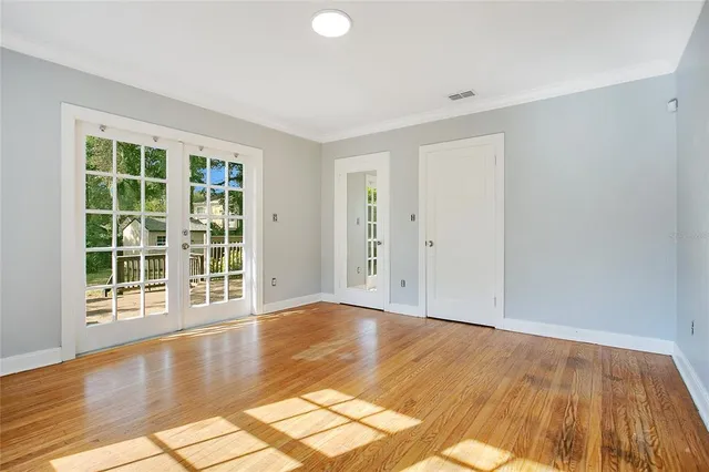 a view of empty room with wooden floor and fan