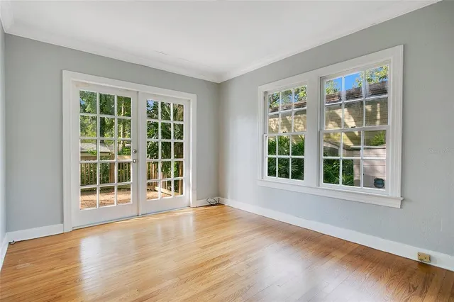 a view of an empty room with wooden floor and windows