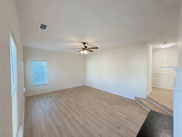 a view of empty room with wooden floor and fan
