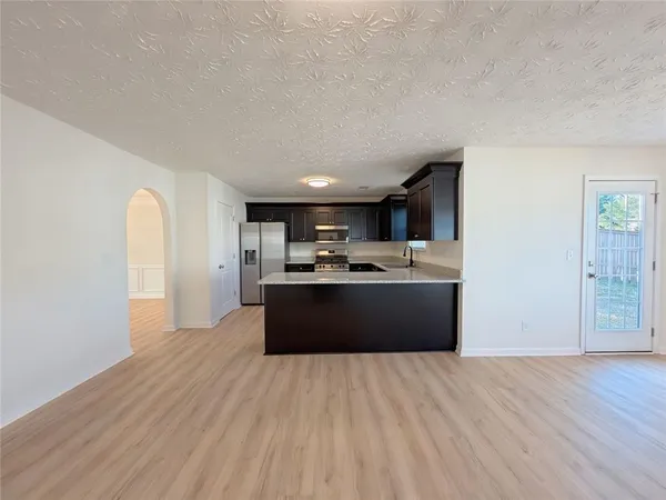 a large room with kitchen island stainless steel appliances wooden floors and view living room