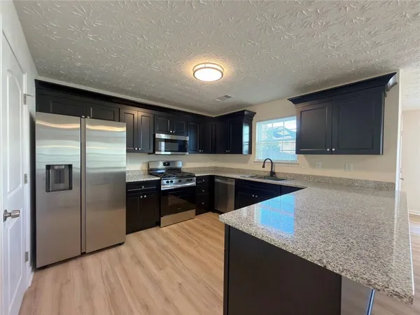 a kitchen with stainless steel appliances granite countertop a refrigerator a sink a stove a microwave and island