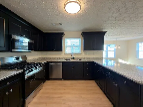 a large kitchen with granite countertop stainless steel appliances and wooden cabinets