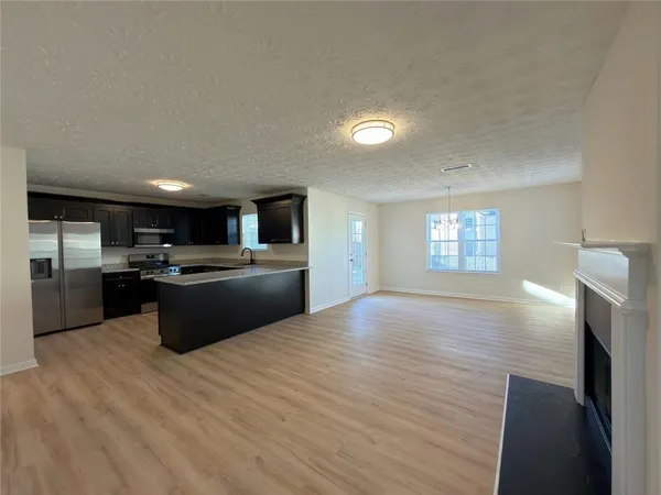 a large kitchen with kitchen island a sink dishwasher a stove and a refrigerator with wooden floor