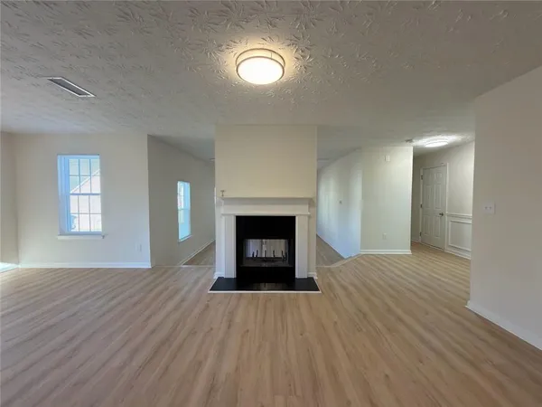 an empty room with wooden floor fireplace and windows