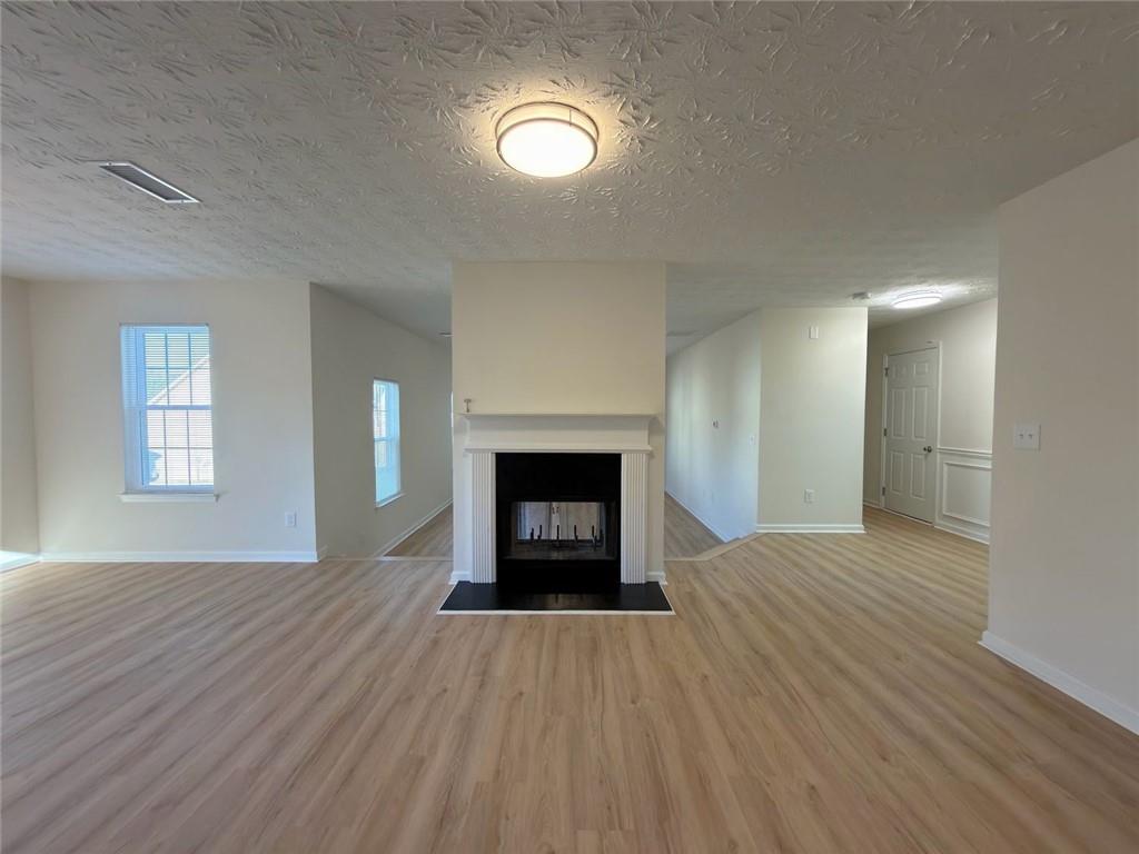 2770 Austin Ridge Drive Northeast Dacula, GA 30019 - Photo 24 of 51 an empty room with wooden floor a fireplace and windows