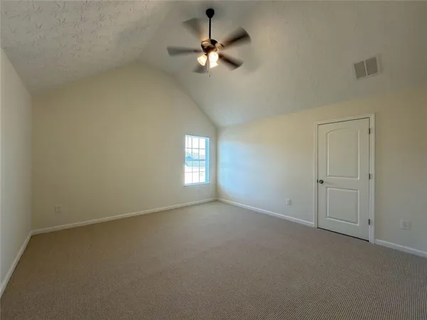 an empty room with a chandelier fan and windows