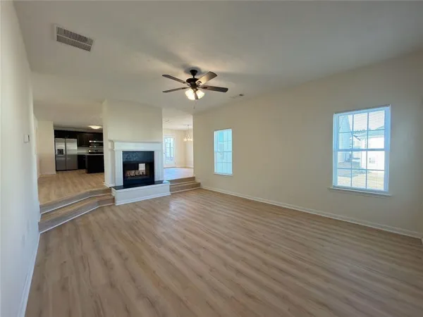 an empty room with windows fireplace and a sink