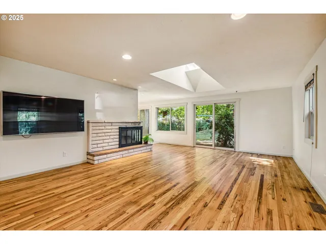a view of empty room with wooden floor and fireplace